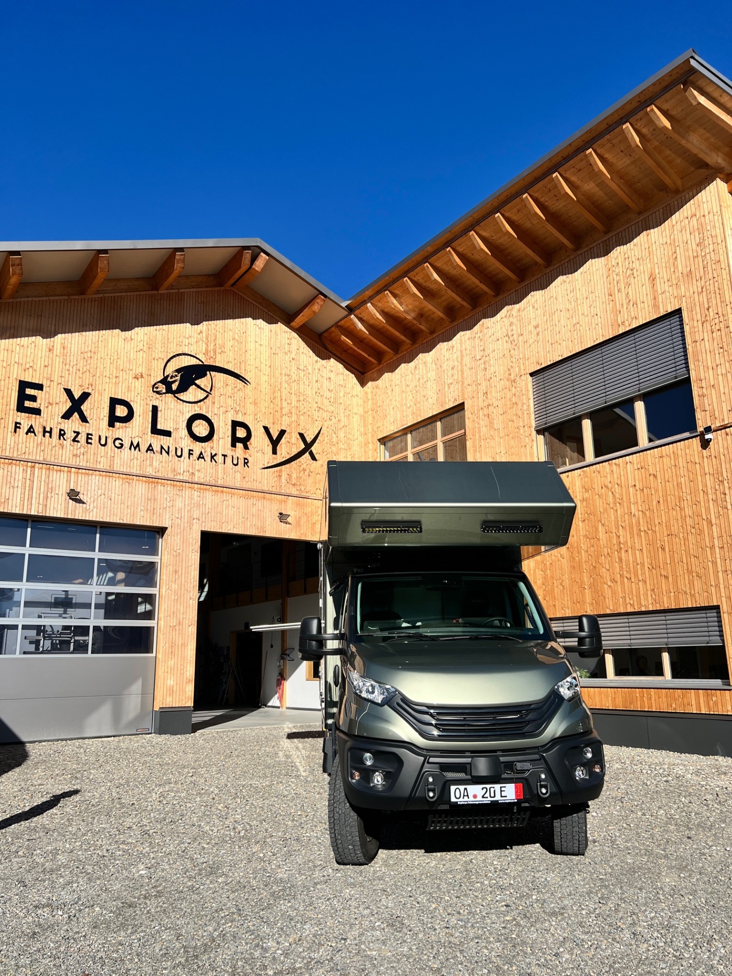 Vor einem Holzgebäude steht unser Iveco Daily 4x4; Firmenlogo „EXPLORVYX“ sichtbar.
